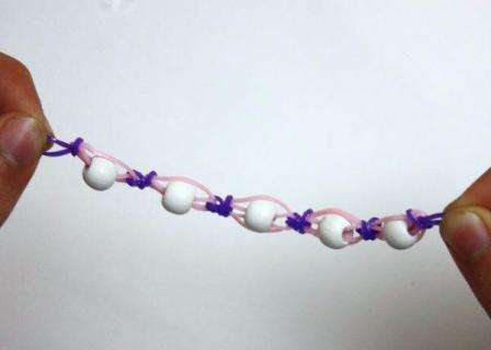 بعد ذلك ، يتم وضع الخرزة مرة أخرى. كرر التضفير حتى يصبح السوار بطول مناسب