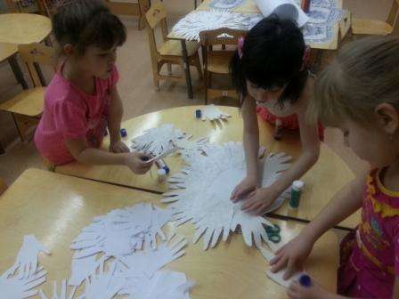 Nyt voit aloittaa kämmenten liimaamisen. Kätevin tapa tehdä tämä on liimapuikolla tai PVA: lla. Pyydä lapsia liimaamaan omat kätensä lumiukon pohjan ympärille. Leikkaa silmän ja nenän yksityiskohdat värillisestä paperista.