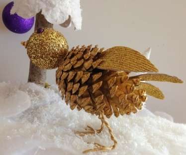 Prilepte krídla medzi borovicové šupiny. Potom môžete začať vyrábať chvost z lepenky. Aby ste to urobili, budete musieť vystrihnúť niekoľko perí, tiež ich zakryť iskrami a lepiť detaily dohromady. Prilepte chvost v oblasti ostrej strany hrbole.