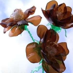 يحتوي كل منزل تقريبًا على زجاجات بلاستيكية ، لذلك لا تتعجل في التخلص منها. خذ زجاجات بنية وخضراء ويمكنك صنع باقة أصلية. اقطع الأوراق من اللون البني ، ولكن بحيث تكون جميعها متصلة ببعضها البعض. ثم تذوب قليلا فوق الشمعة. اصنع اثنين من هذه الفراغات ، ثم تلصقها معًا.